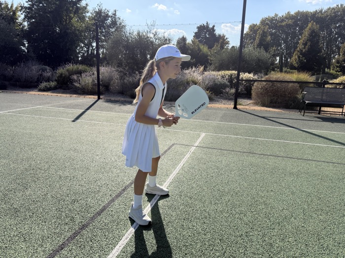 A young player preparing to return a ball with an Elevated paddle